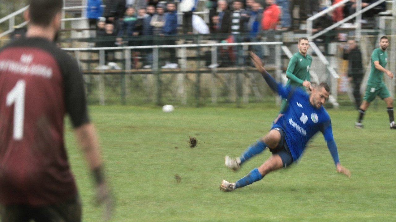 A footballer sliding across wet grass during the match