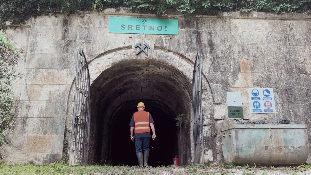A worker at the mine entrance beneath the word Sretno