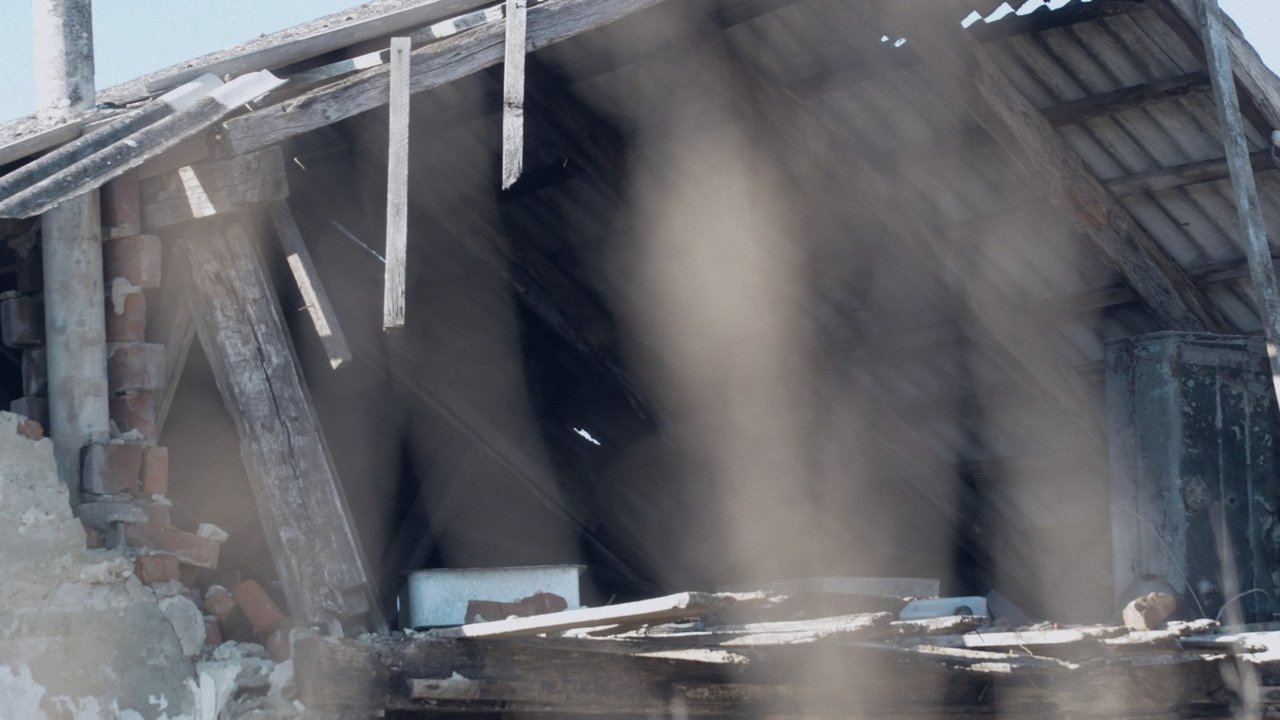 A damaged home seen through dust and debris